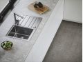 Alveus pomivalno korito z odcejalno površino v beli kuhinji kjer se na pultu nahaja deska za rezanje in skleda z avokadom